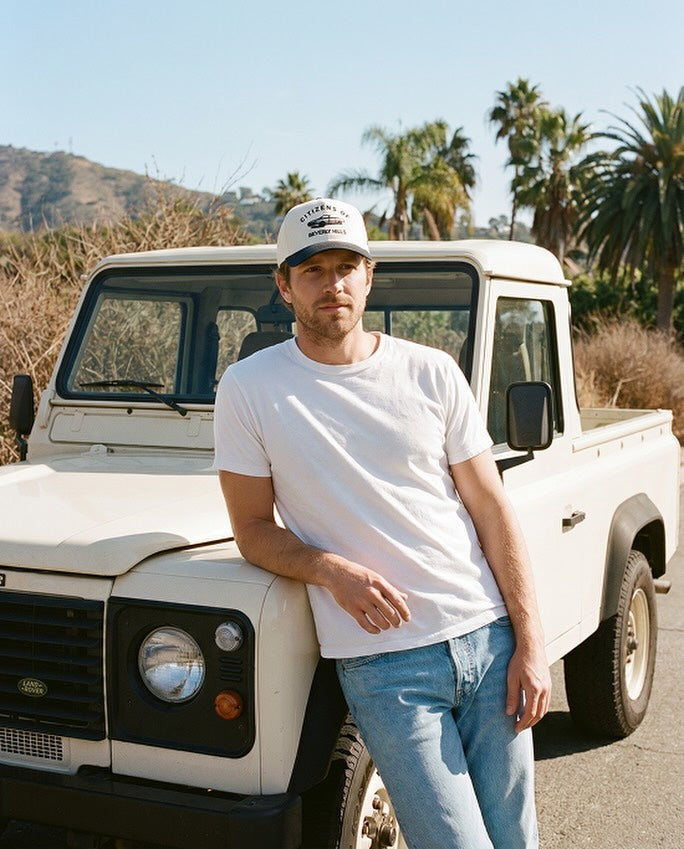 Citizens of Beverly Hills — model leaning against a vintage Land Rover truck